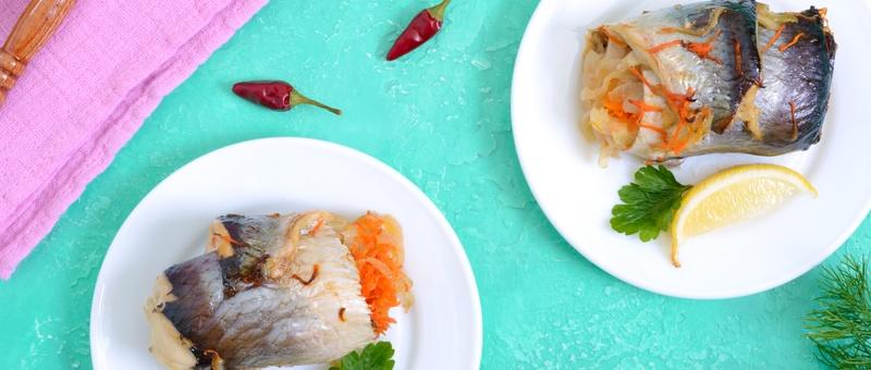 Top view of two baked herring rolls stuffed with vegetables on white plates with lemon, herb and whole chilli garnish beside pink napkin and brown-handled eating utensil against a vibrant blue/green background.