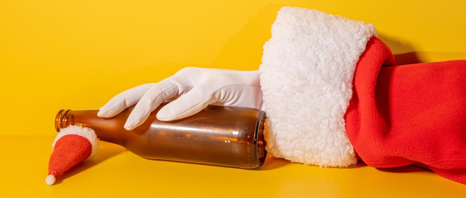 Santa Claus holding beer bottle with his hands on yellow background