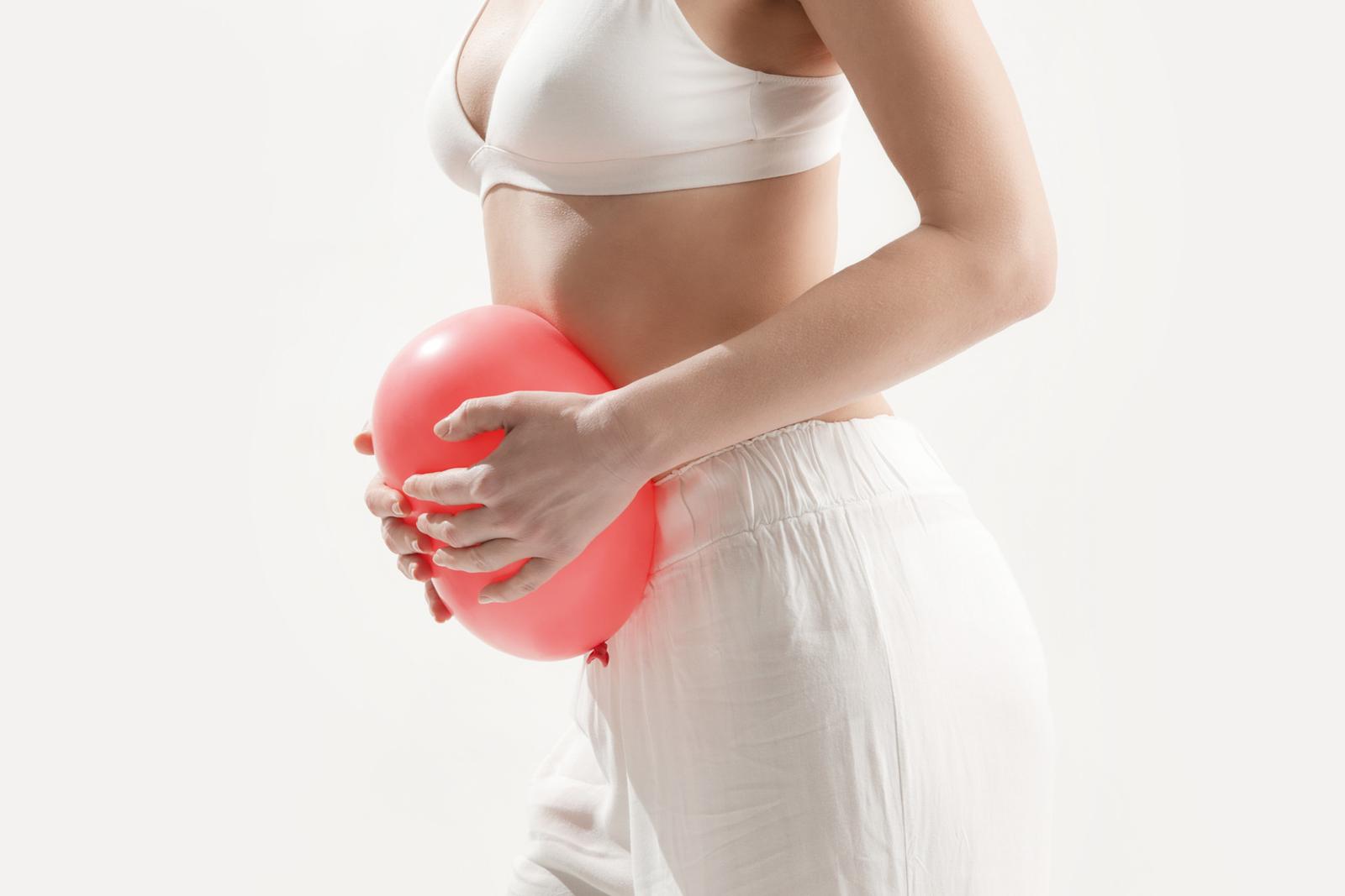 Woman clutching a balloon to her stomach to symbolise trapped wind.